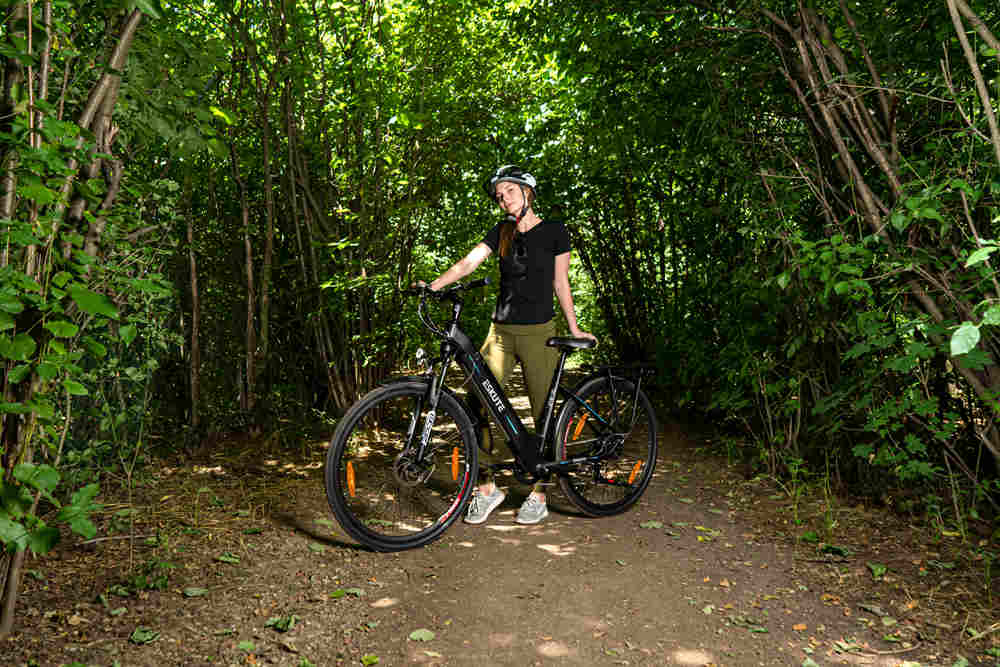 Frau mit Helm steht neben dem Polluno Hybrid E-Bike